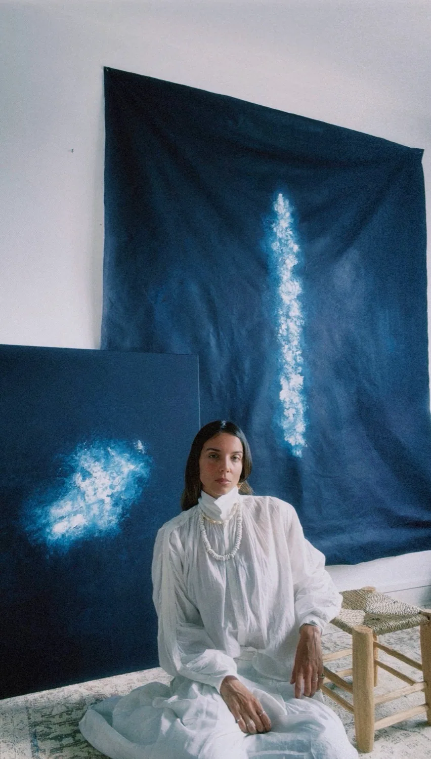 Assise devant une grande toile bleue