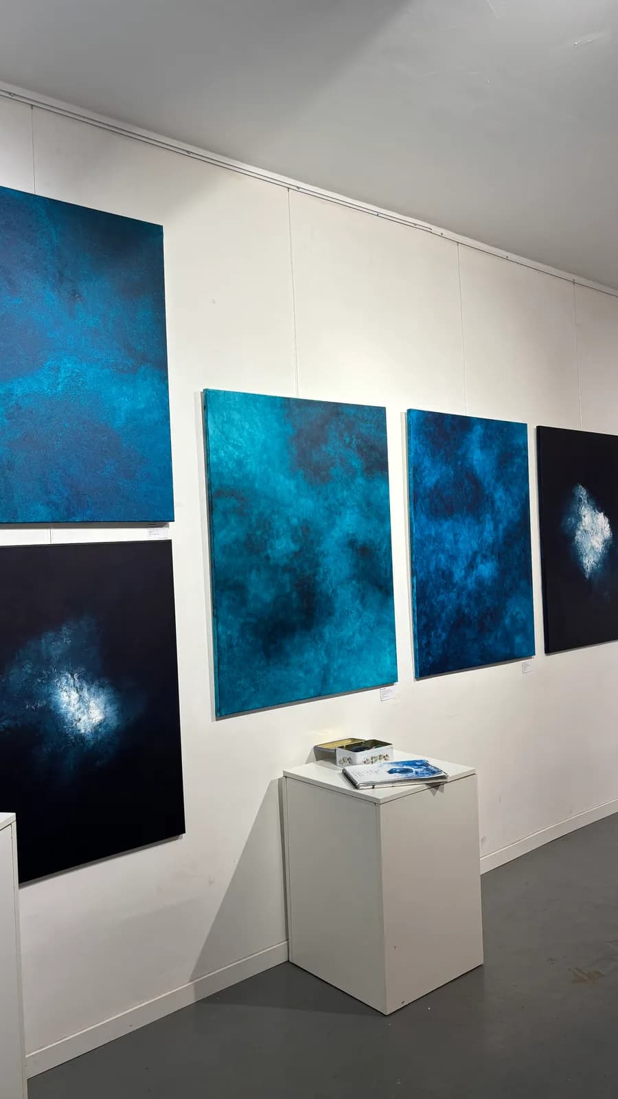 Cinq toiles bleues accrochées sur les cimaises blanches de la galerie Kiff & Marais