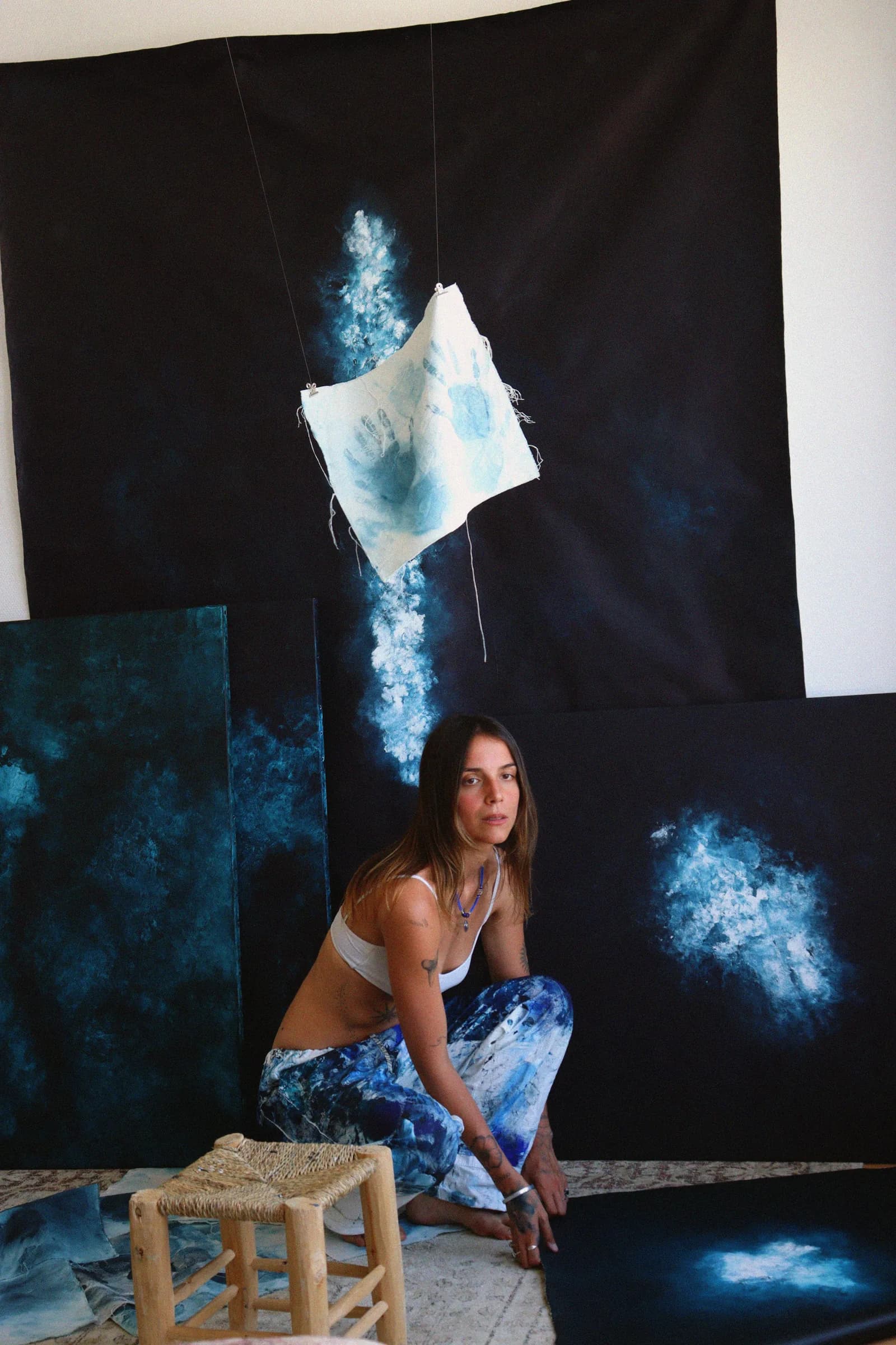 Dans mon atelier, accroupie parmi les toiles, une pièce de lin suspendue
