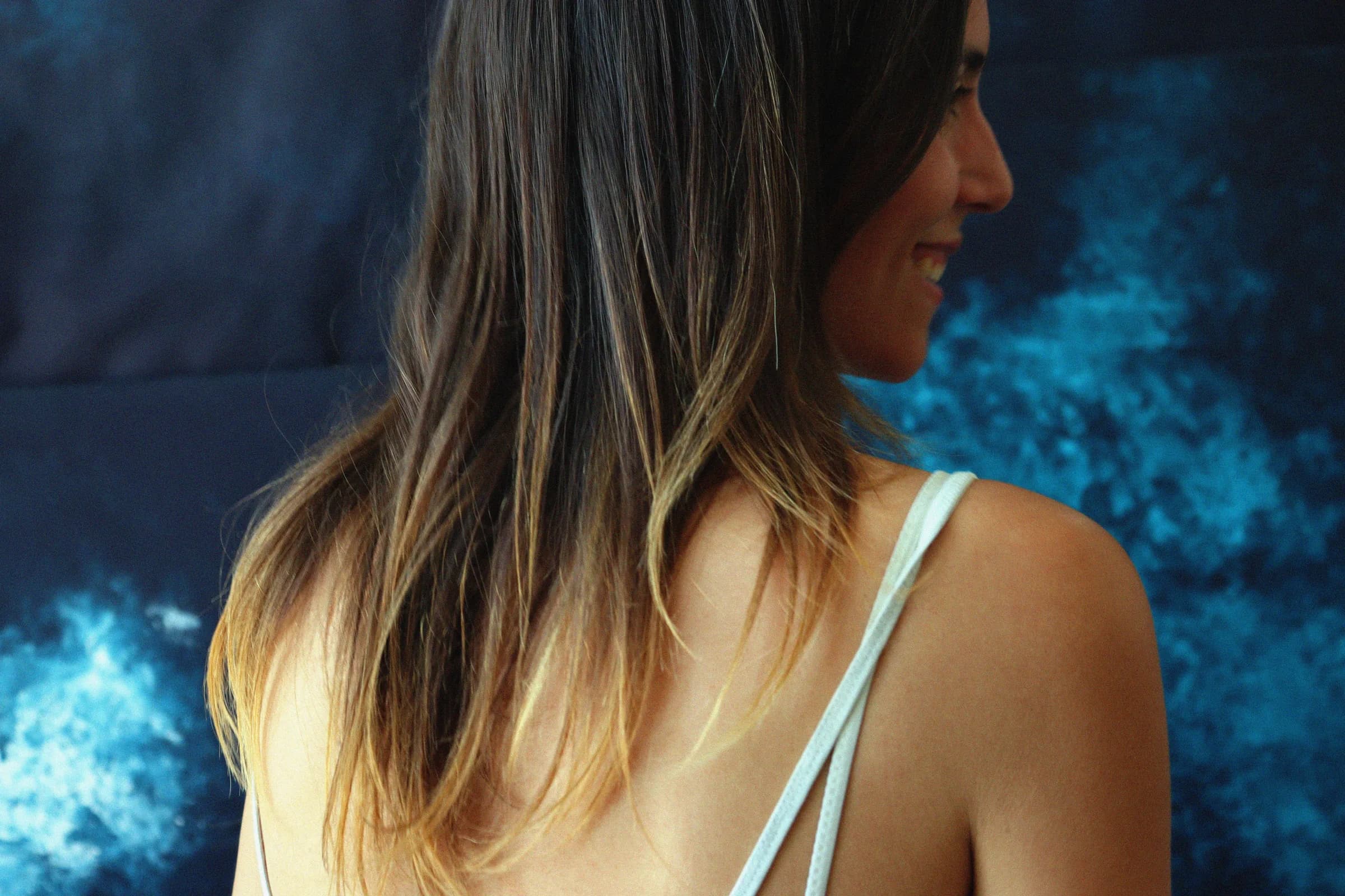 De dos, le sourire tourné vers la toile bleu nuit