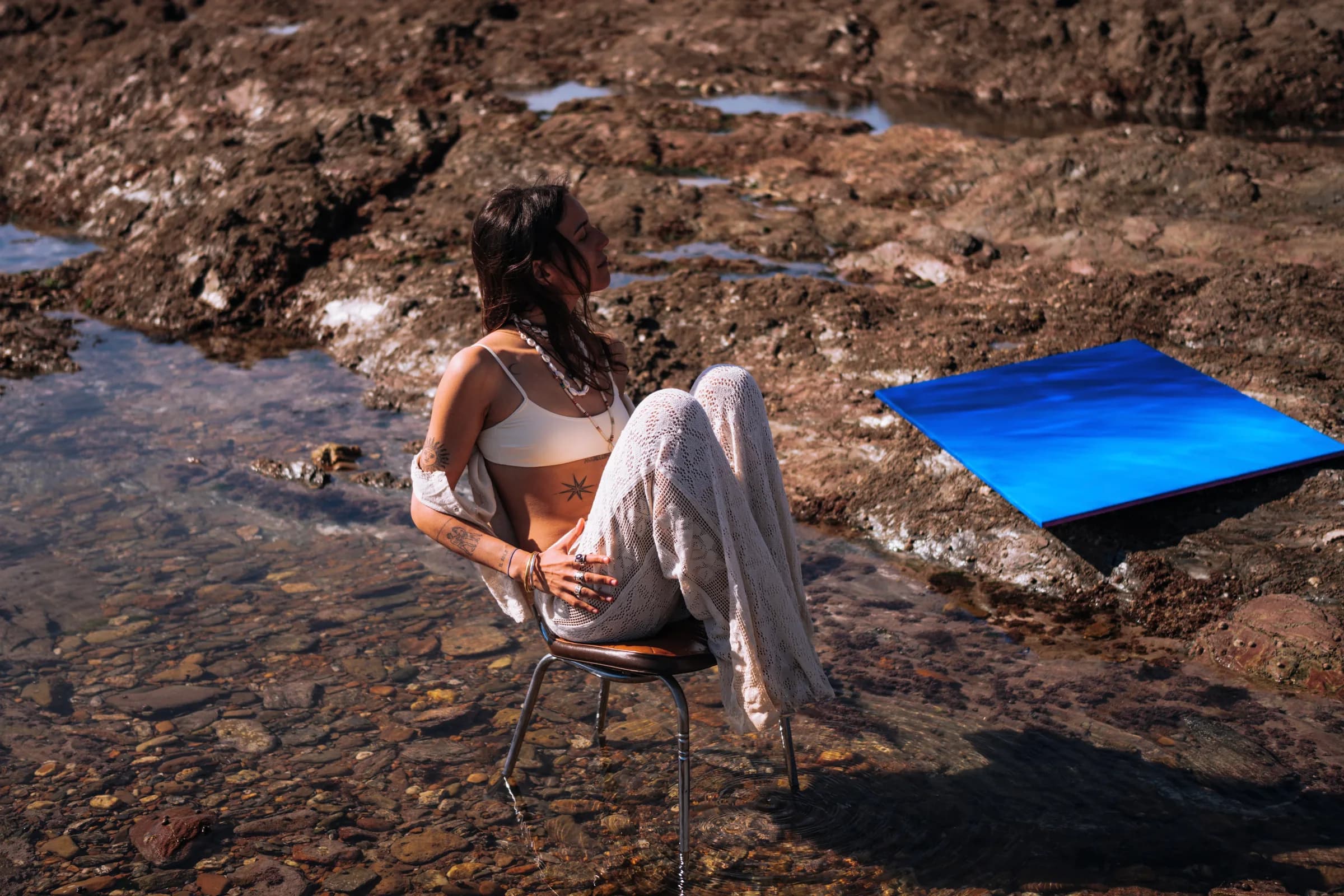 Assise sur une chaise au milieu de l'eau, la toile posée sur la roche