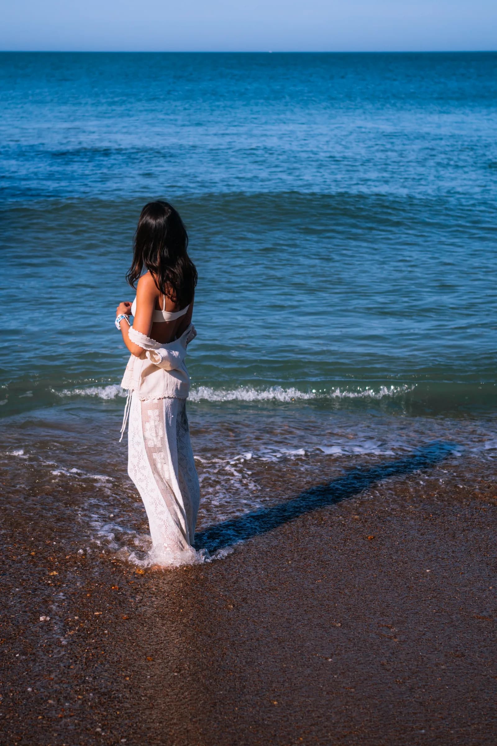 De dos face à l'horizon, les pieds dans l'eau