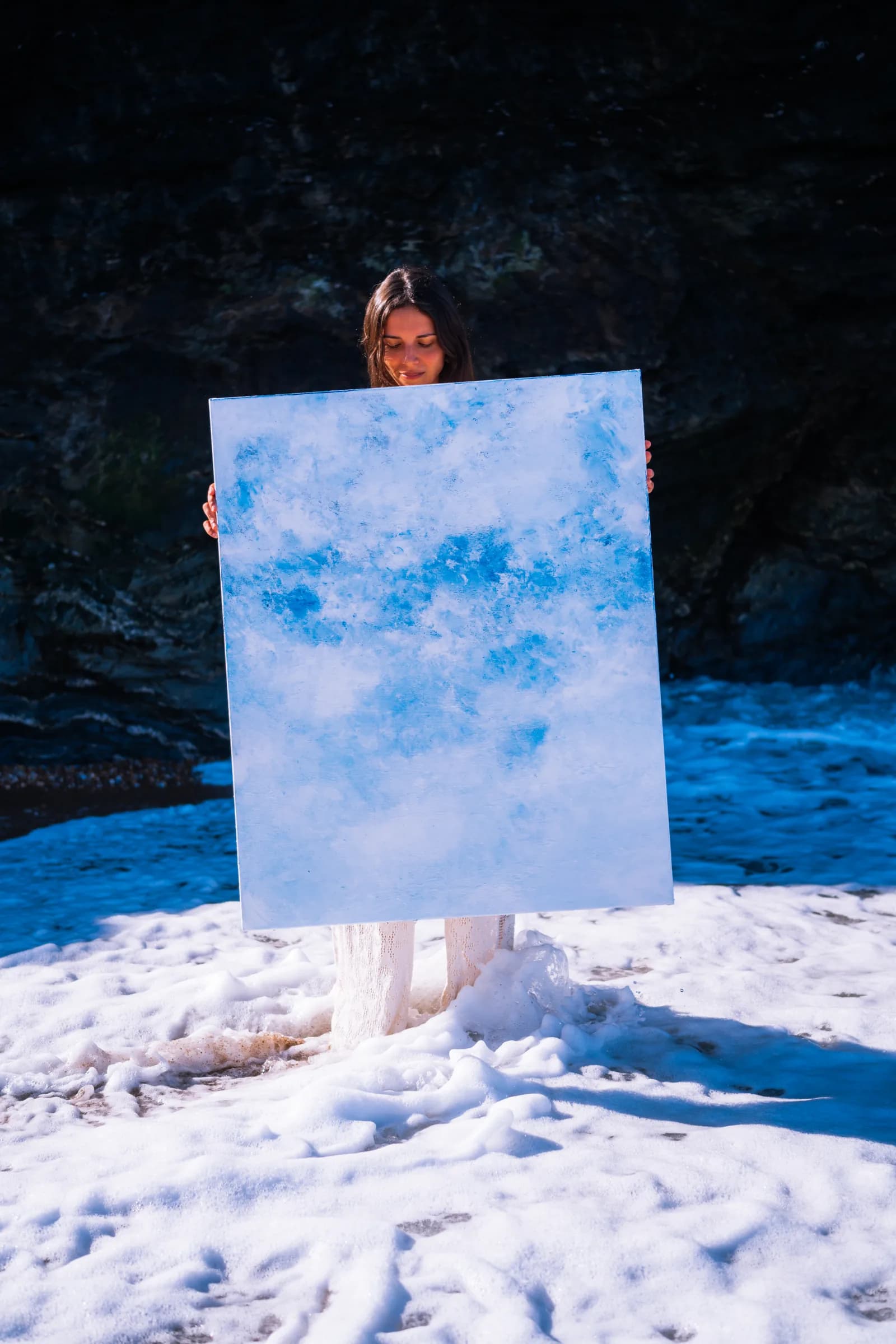 Portant la toile claire, l'écume jusqu'aux chevilles