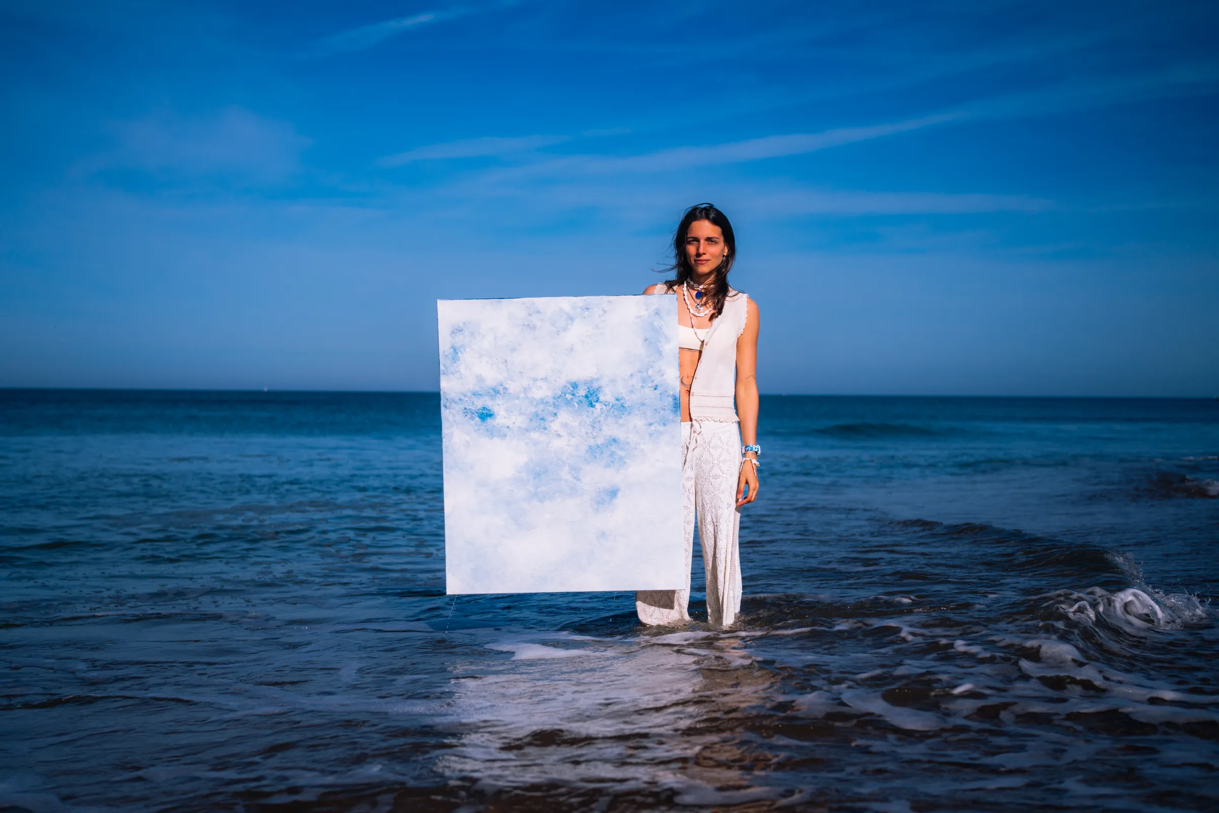 Debout dans la mer, la toile claire à bout de bras