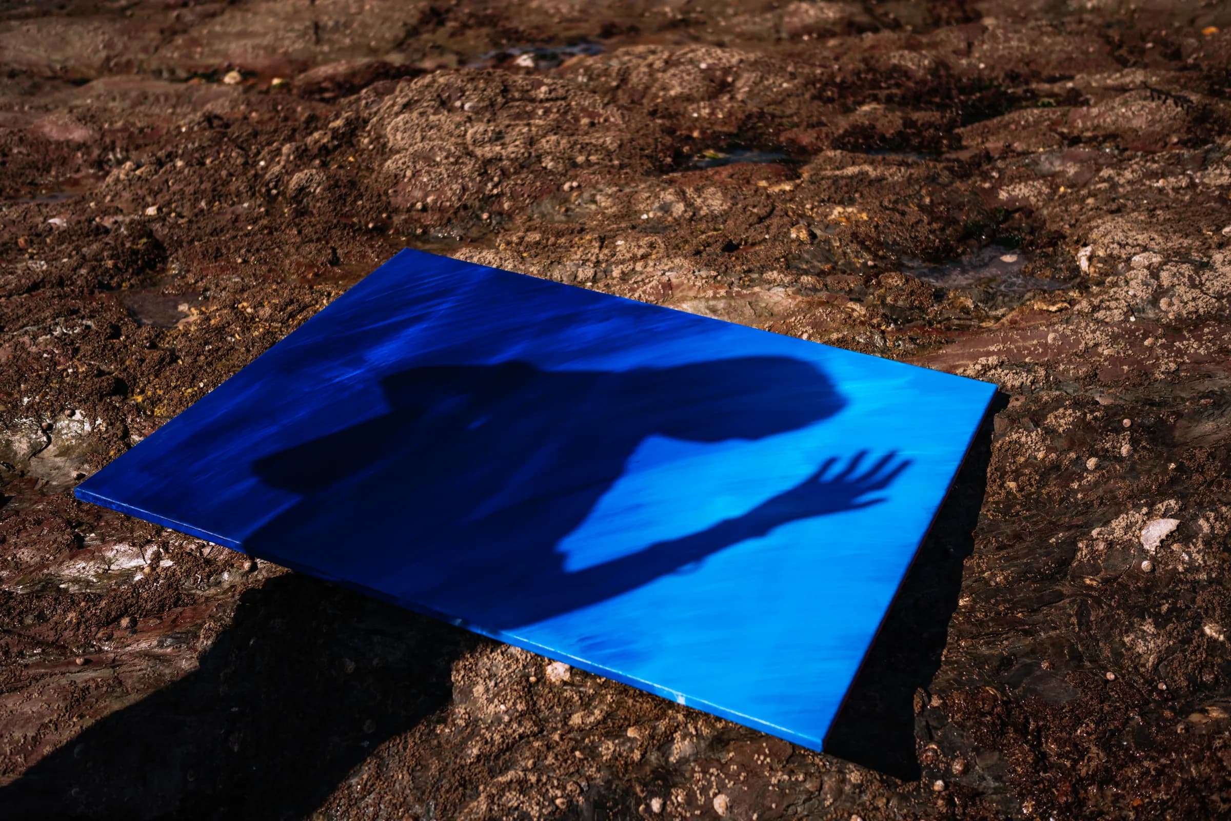 L'ombre d'une silhouette portée sur une toile bleue posée sur la roche