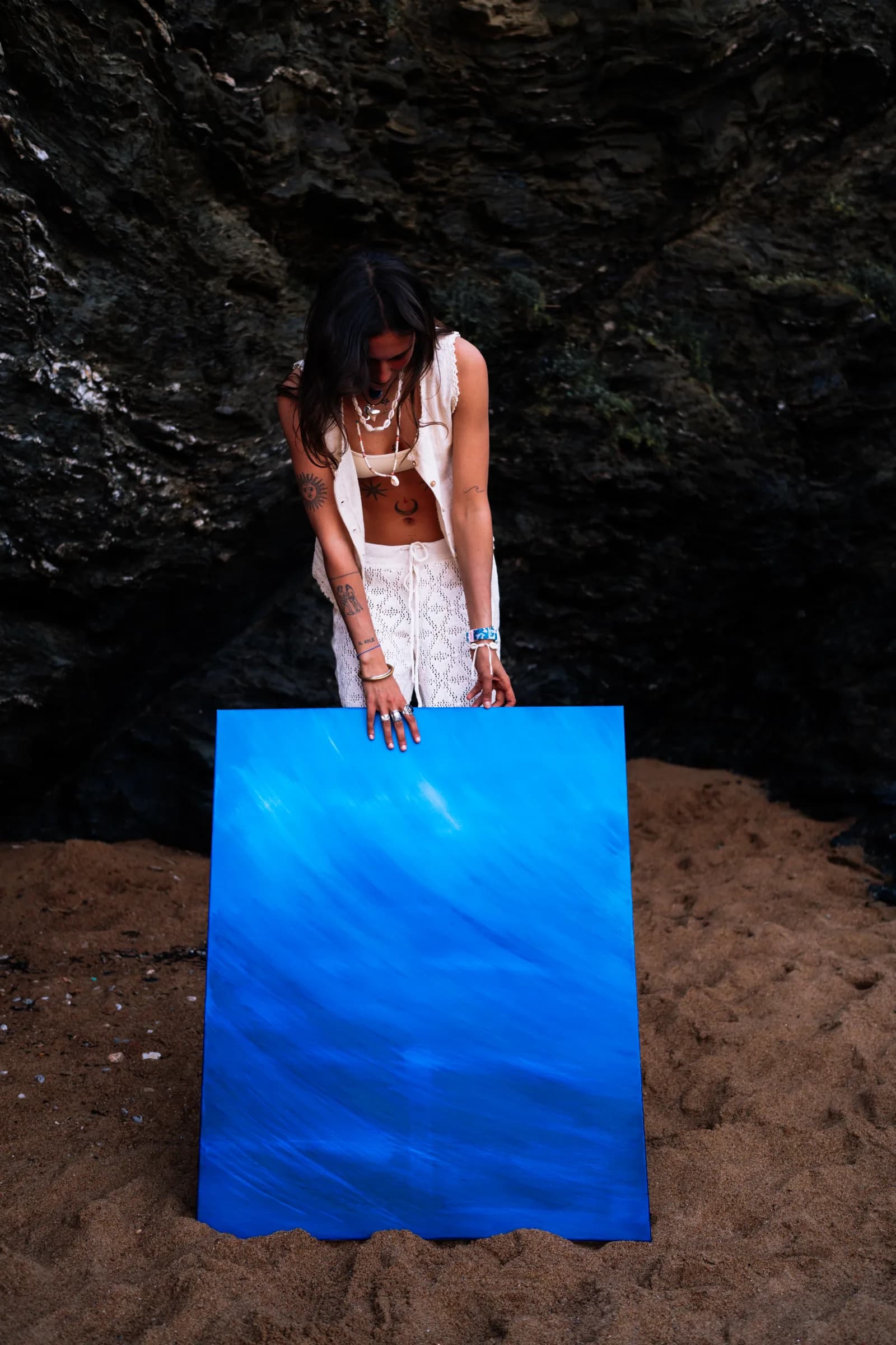 Penchée au-dessus de la toile posée sur le sable